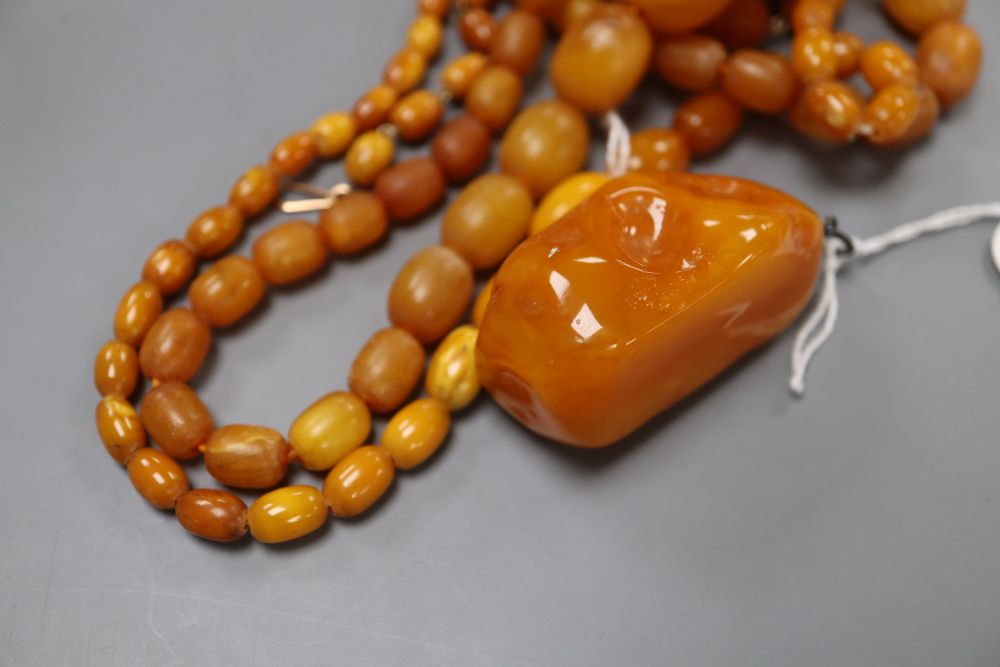 Four assorted amber bead necklaces (1 a.f.) and an amber boulder pendant, gross weight 82 grams.